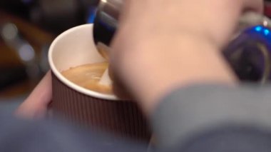 Barista kadın süt kahve ekler ve desenli bir yaprak üzerinde süt köpüğü latteart hale getirir.