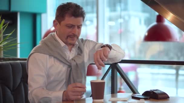 Взрослый мужчина в белой рубашке добавляет сахар в свежий утренний кофе — стоковое видео