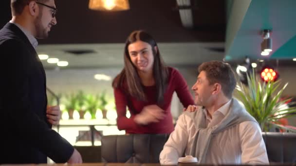 Jonge brunette meisje introduceert haar vriendje met haar vader in een café — Stockvideo