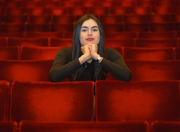 Elleri boş kırmızı tiyatro salonda oturmuş onun yüzünü altında olan esmer kız