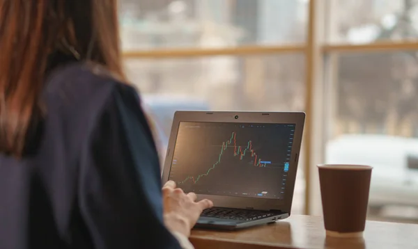 Esmer kız düşen Döviz grafik laptop üzerinde saatler