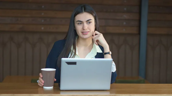 Önemli bir karar vermeden önce bir dizüstü bilgisayar ve kahve ile esmer kız düşünüyor