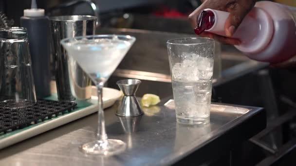 Barman versa sciroppo rosso in un bicchiere con ghiaccio, primo piano del cocktail Cosmopolitan — Video Stock