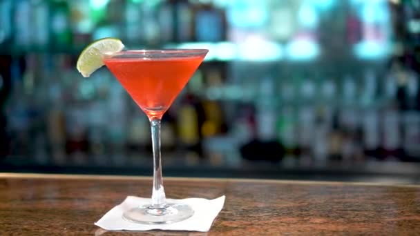 Красный напиток в бокале мартини на барной стойке, крупным планом коктейля Cosmopolitan — стоковое видео
