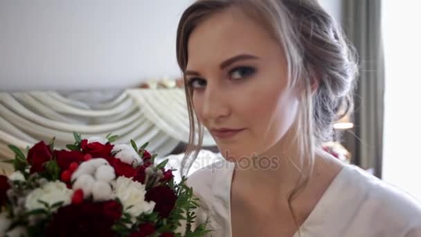 Junge Braut riecht die Blumen und blickt dann in die Kamera — Stockvideo