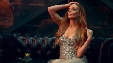 Bir deri kanepe ve Rüzgar üzerinde oturan muhteşem elbiseli güzel kız saçını dalgalar