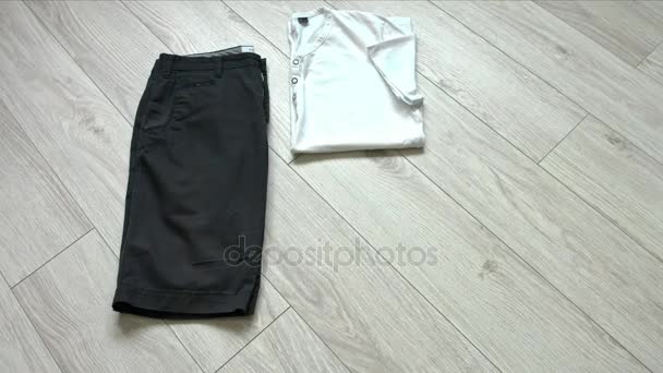 Mens casual kläder inklusive mörk blå shorts, vit skjorta, Jeansskjorta, vita sneakers och tillbehör. Platt lekmanna, top view. — Stockvideo