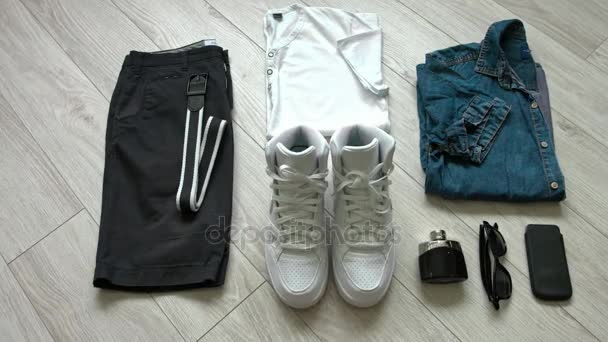 Casual Outfits für Herren mit dunkelblauen Shorts, weißem Hemd, Jeanshemd, weißen Turnschuhen und Accessoires. flache Lage, Draufsicht. — Stockvideo