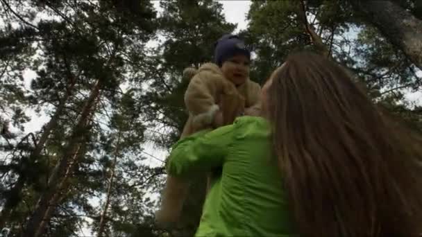 Mère élève le bébé au-dessus de lui dans les bois 