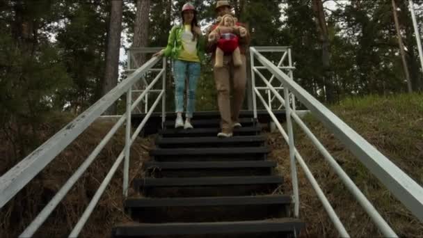 Una familia joven con un niño bajando las escaleras hacia el mar — Vídeo de stock