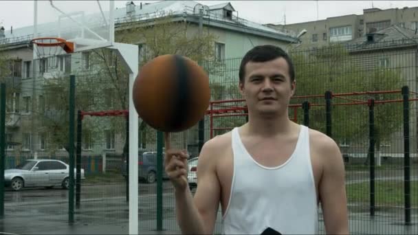 O cara girando uma bola de basquete em seu dedo na área aberta — Vídeo de Stock