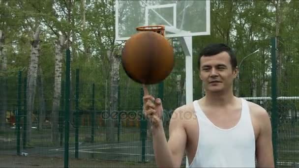 Bir basketbol üstünde onun parmak açık alan üzerinde dönen adam — Stok video