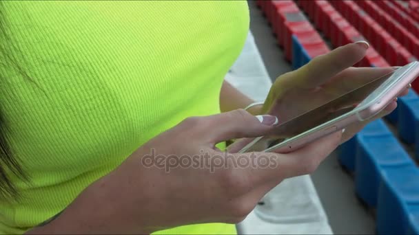 A menina olha para o telefone em um estádio de esportes. Close-up — Vídeo de Stock