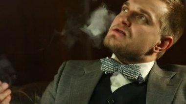 Yakışıklı genç bir puro barda sigara pahalı bir takım elbise. Yakın çekim