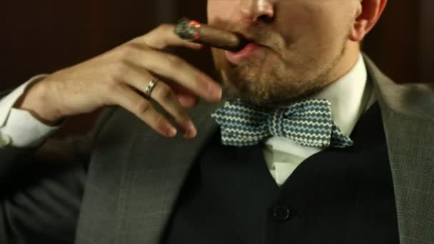 Joven guapo con un traje caro fumando un cigarro en el bar. Primer plano — Vídeos de Stock