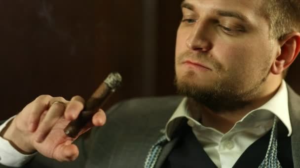 穿着昂贵西装的英俊年轻男子在酒吧里抽雪茄。特写 — 图库视频影像