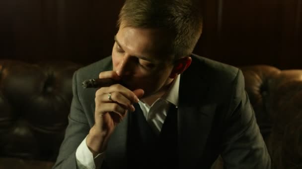 Schöner junger Mann im teuren Anzug, der in der Bar eine Zigarre raucht. Nahaufnahme — Stockvideo