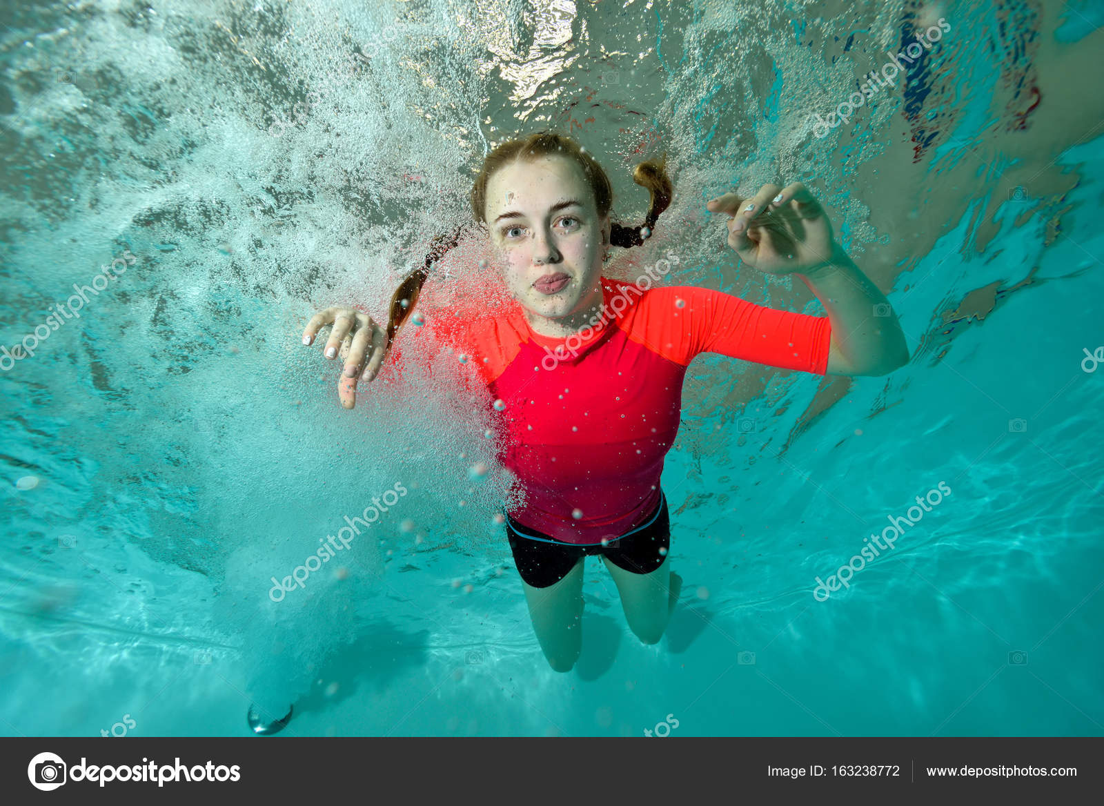 Schöne Mädchen Schwimmt Unter Wasser In Einem Roten Badeanzug Auf Blauem Hintergrund Und Schaut