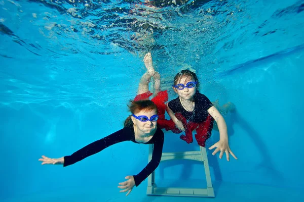 İki küçük kızlar yüzme ve havuz ve bana bakıp altına dalış sualtı, oynarken. — Stok fotoğraf