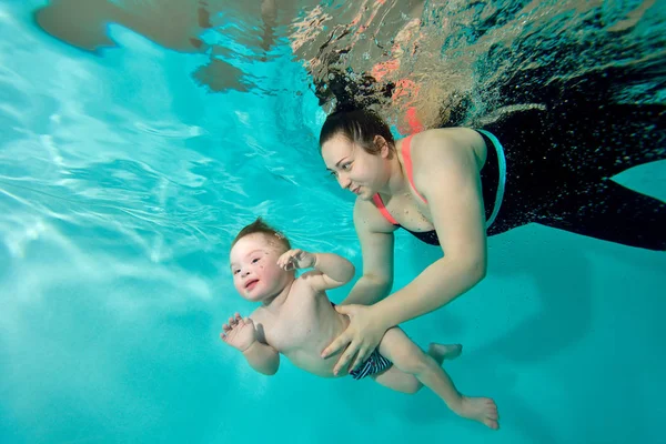 Instructor, mamá enseña y ayuda al bebé a nadar bajo el agua en la piscina . — Foto de Stock