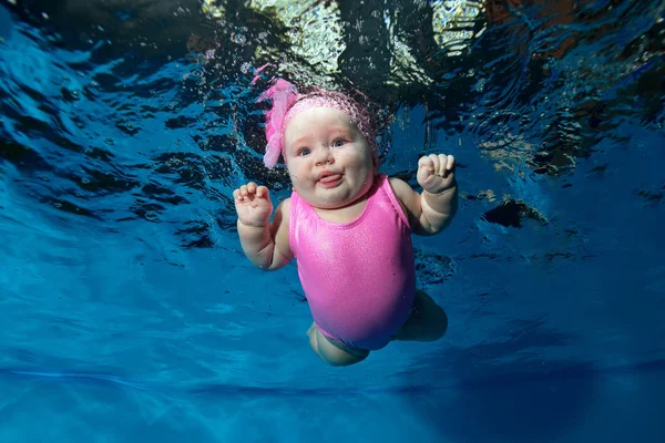 Baby Swims Underwater Pool Blue Background Pink Dress Looking Camera — Stock Photo, Image