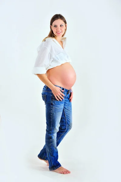 Beyaz arka plan üzerinde poz ve gülümseyen hamile kız — Stok fotoğraf