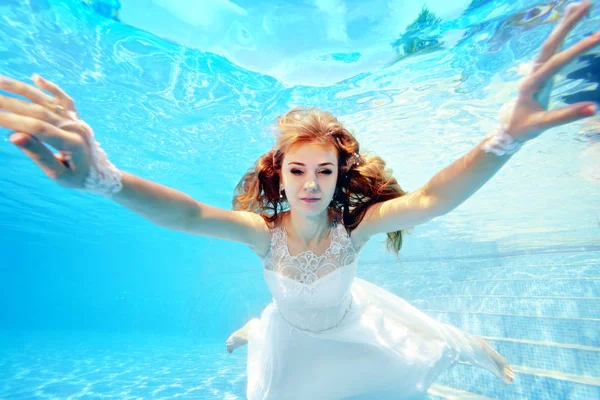 穿着白衣的新娘在水下向摄影机游去 水平方向 从水下的景色 — 图库照片