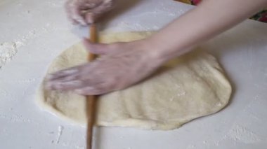 Kız beyaz bir tabloda hamur rulo ve bir pizza kalıptan hazırlar.