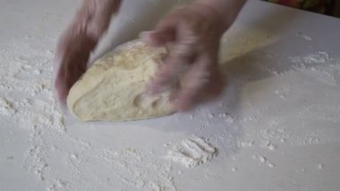 Kız büyük bir parça hamuru alır ve beyaz bir tablo üzerinde çalışırken başlar.