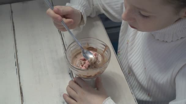 A little girl sits in a cafe and eats ice cream from a glass Cup. The view from the top. — Stock Video