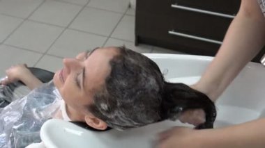 Güzellik Salonu bir esmer kız başkanı şampuanlama Kuaför stilist. Baş masaj ve ter saçlarının arasından bulaşması. Kız gülüyor ve gülümsüyor. Yakın çekim, yüksek detay. 4 k. 25 fps