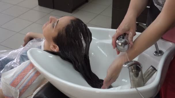 理髪店は シャワーからの水の彼女の頭に水をまくシンク上の理髪店のブルネットの少女の頭から石鹸の泡を洗います クローズ アップ 高詳細 Fps — ストック動画