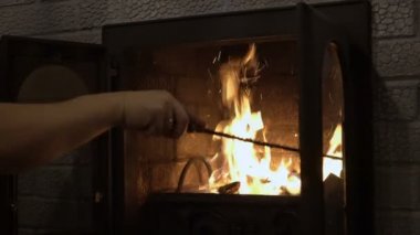 Bir adam yanan bir şöminede odun karıştırıyor. - Yakın çekim. 4k.