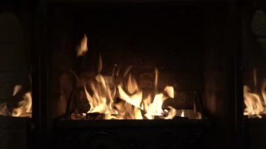 A bright fire inside the fireplace behind glass doors against a brick wall. The fireplace doors open and then close without human intervention. Concept. Symbol. Shooting without people. Closeup. 4K.