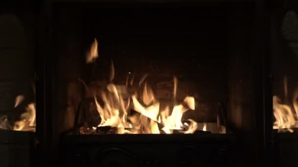 A bright fire inside the fireplace behind glass doors against a brick wall. The fireplace doors open and then close without human intervention. Concept. Symbol. Shooting without people. Closeup. 4K. — Stock Video