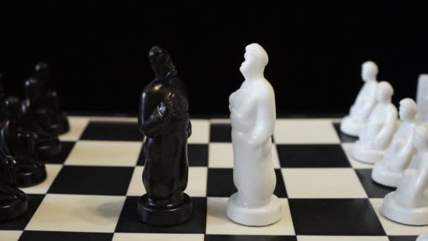 Des figures de roi des échecs blanc et noir se dressent l'une en face de l'autre sur un échiquier noir et blanc. Pièces d'échecs sous la forme d'un homme-cosaque slave. Gros plan. Rotation. Concept. 4K . — Video