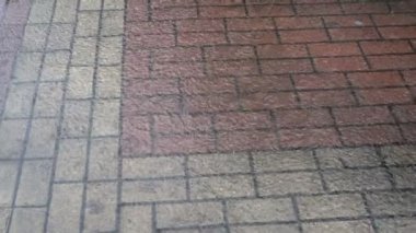 Kasvetli bir günde şehrin kaldırımındaki su birikintisine küçük yağmur damlaları düşer ve suyun yüzeyinde daireler çizer. Yukarıdan manzara. Yakın çekim..