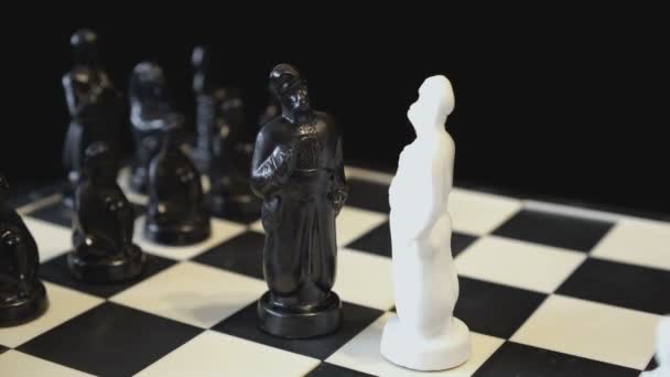 Két fekete-fehér sakk-király néz szembe egymással egy forgó fekete-fehér sakktáblán. Sakkfigurák egy szláv férfi-kozák formájában. Közelkép. Fogantatás. 4k. — Stock videók