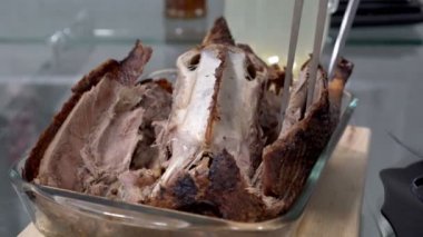 Bir adamın mutfakta cam bir tabakta büyük bir mutfak bıçağıyla kestiği kızarmış ördeğin yakın çekimi. Aile tatili. Kapatın. Yukarıdan manzara. Yüzsüz. 4k.