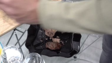 Bir adam mutfaktaki siyah bir tabaktan sıcak ördek parçalarını keser ve üzerine koyar. Aile kutlaması. Yakın plan. Yukarıdan manzara. Yüzsüz. 4k.