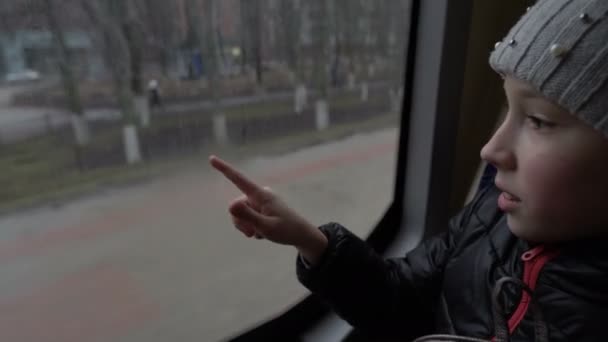 Šťastná holčička přitáhne srdce prstem na zamlžené sklo okna autobusu a usměje se. Detailní záběr. Koncept dětského štěstí. 4K. — Stock video