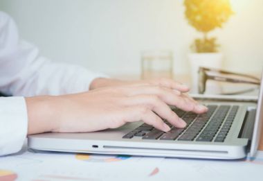 İş kadını dizüstü bilgisayarda el yazısı yazıyor.