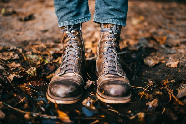 Çürük İtalyan hippi çizik çizik çizikleri içinde su birikintisinde duran bir adamın bacaklarına yakın çekim. Islak ve çiğ sonbahar. Sonbahar renkleri. Portakal yaprakları, suda çam kozalakları. Tuhaf bir kavram..