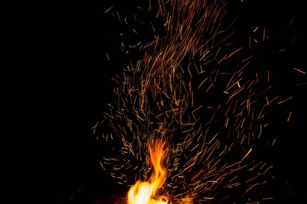 Centelhas de fogo e chamas em movimento sobre fundo preto. Textura e erupção — Fotografia de Stock