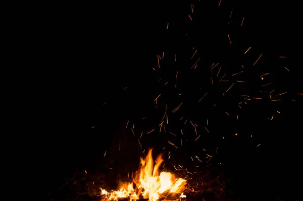 Chispas de fuego y llamas en movimiento sobre fondo negro. Textura y erupción —  Fotos de Stock