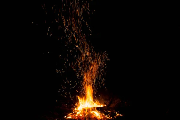 Ildgnister og flammer i bevegelse på svart bakgrunn. Tekstur og utbrudd – stockfoto