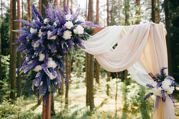 Ahşap arch çiçekler ile evlilik töreni için düğün, perde ve diğer dekorasyon öğeleri Instalar ormanda yer. Çam ağaçları içinde güneşli yaz günü. Kutlama ruh. Cam, tüyler mumlar