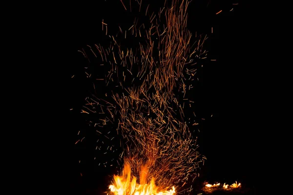 Ogień iskrzy i płomienie w ruchu na czarnym tle. Tekstura i erupcja — Zdjęcie stockowe