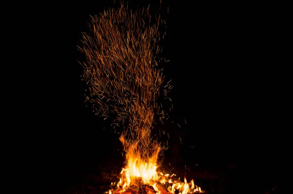 Étincelles de feu et flammes en mouvement sur fond noir. Texture et éruption — Photo