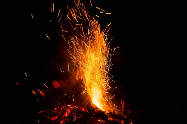 Fire sparks and flames in motion on black background. Texture and eruption — Stock Photo, Image